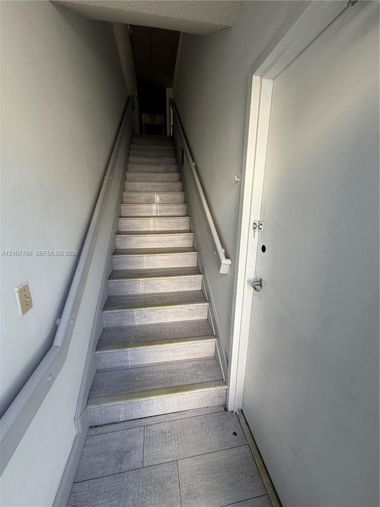 Staircase featuring wood-finish flooring, neutral wall tones, and dual wall-mounted handrails