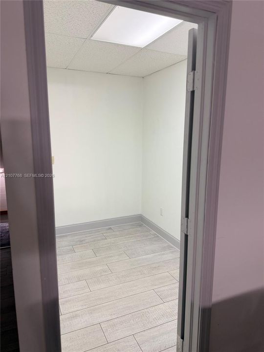 Interior room featuring wood-finish tile flooring, neutral walls, and a recessed drop-ceiling light fixture