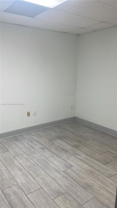 Interior space featuring gray-toned tile flooring and a suspended ceiling grid