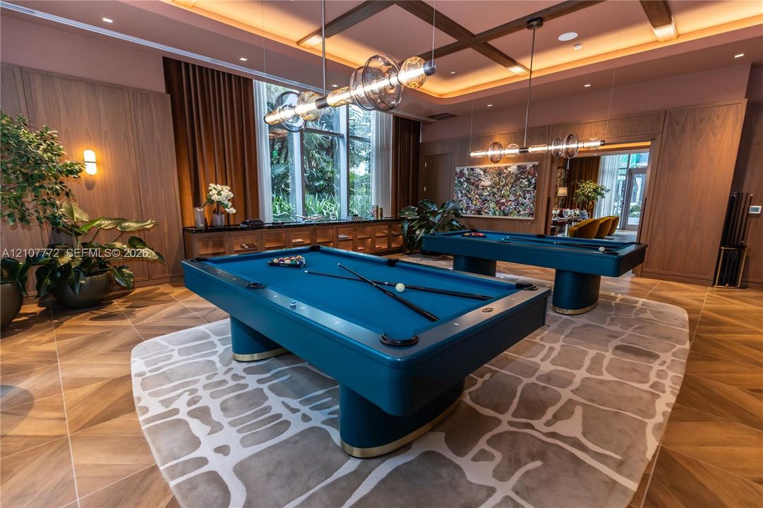Wood-finish flooring, coffered ceiling with recessed lighting, floor-to-ceiling wood wall paneling, built-in cabinetry, and multi-light linear pendant fixtures