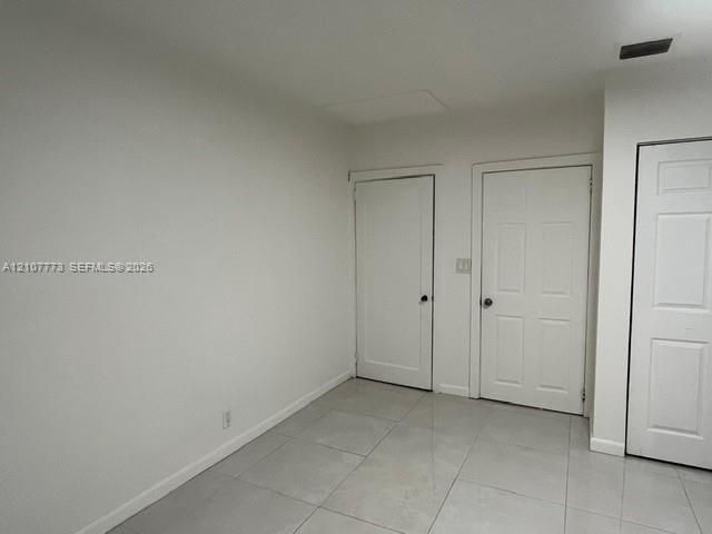 Neutral-toned interior space featuring light-colored tile flooring, smooth wall finishes, and multiple six-panel doors