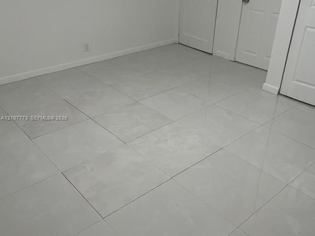 Large-format light gray tile flooring with high-gloss finish, paired with white panel doors