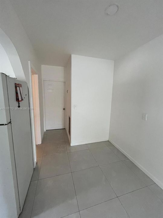 Large-format neutral floor tiling, recessed ceiling lighting, and a paneled interior door
