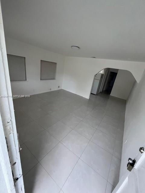 Neutral-toned ceramic tile flooring, arched wall detailing, and flush-mount ceiling lighting