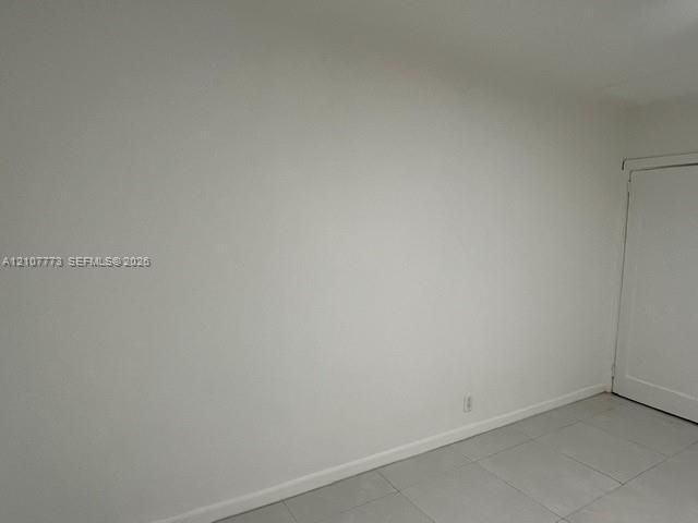 Interior space featuring white-painted walls and light-toned tile flooring, including a single-panel interior door