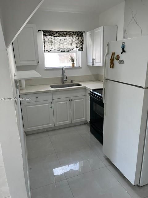 Kitchen featuring white cabinetry, solid-surface countertops, tile flooring, stainless steel sink with high-arc faucet, and black built-in oven