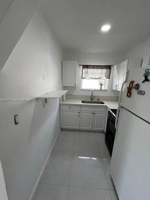Kitchen featuring white shaker-style cabinetry, solid-surface countertops, recessed lighting, and tiled flooring