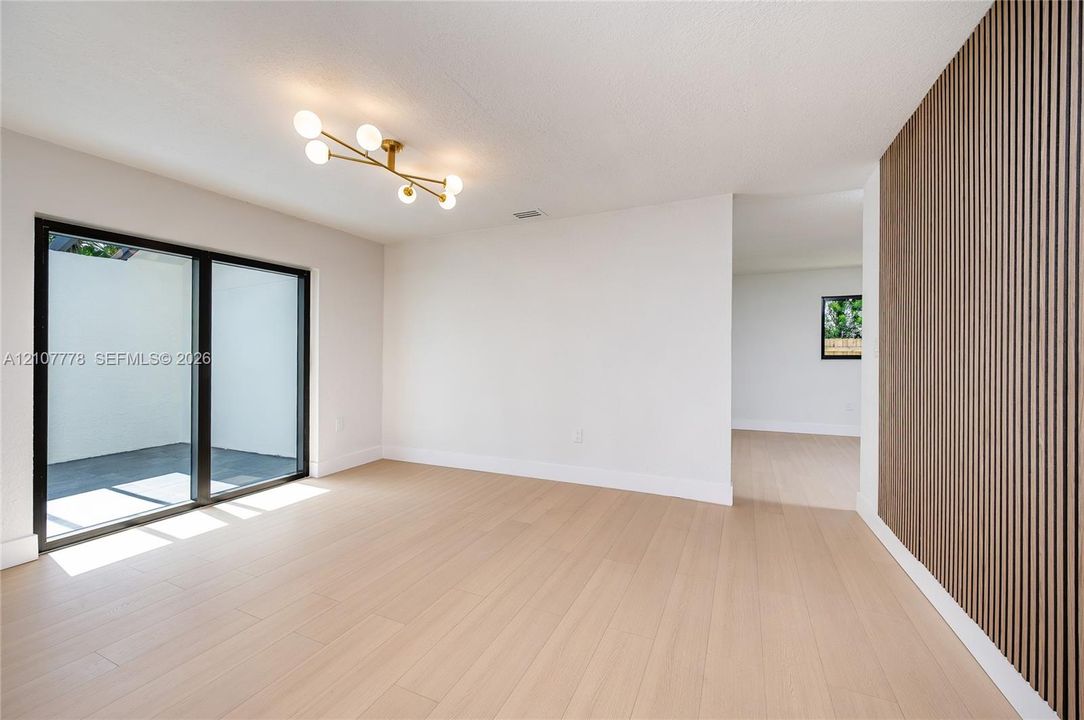 Interior space featuring wood-finish flooring, a decorative vertical slat wall treatment, and a multi-globe pendant light fixture