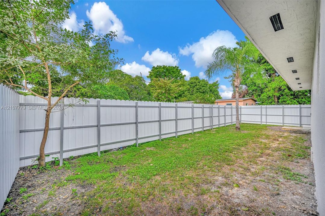 Private rear yard enclosed by white vinyl privacy fencing with a covered patio featuring recessed lighting