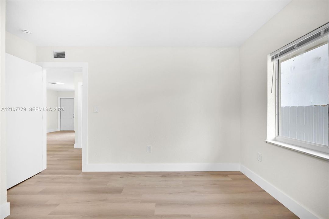 Neutral wall tones paired with light-toned wood-finish flooring and a single-pane window