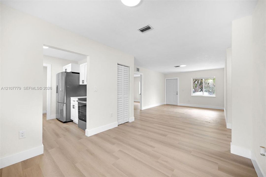 Open floor plan featuring wood-finish flooring, stainless steel kitchen appliances, white cabinetry, and recessed lighting