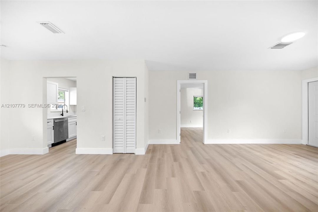 Open-concept living space featuring wood-finish flooring, white walls, and a bi-fold closet