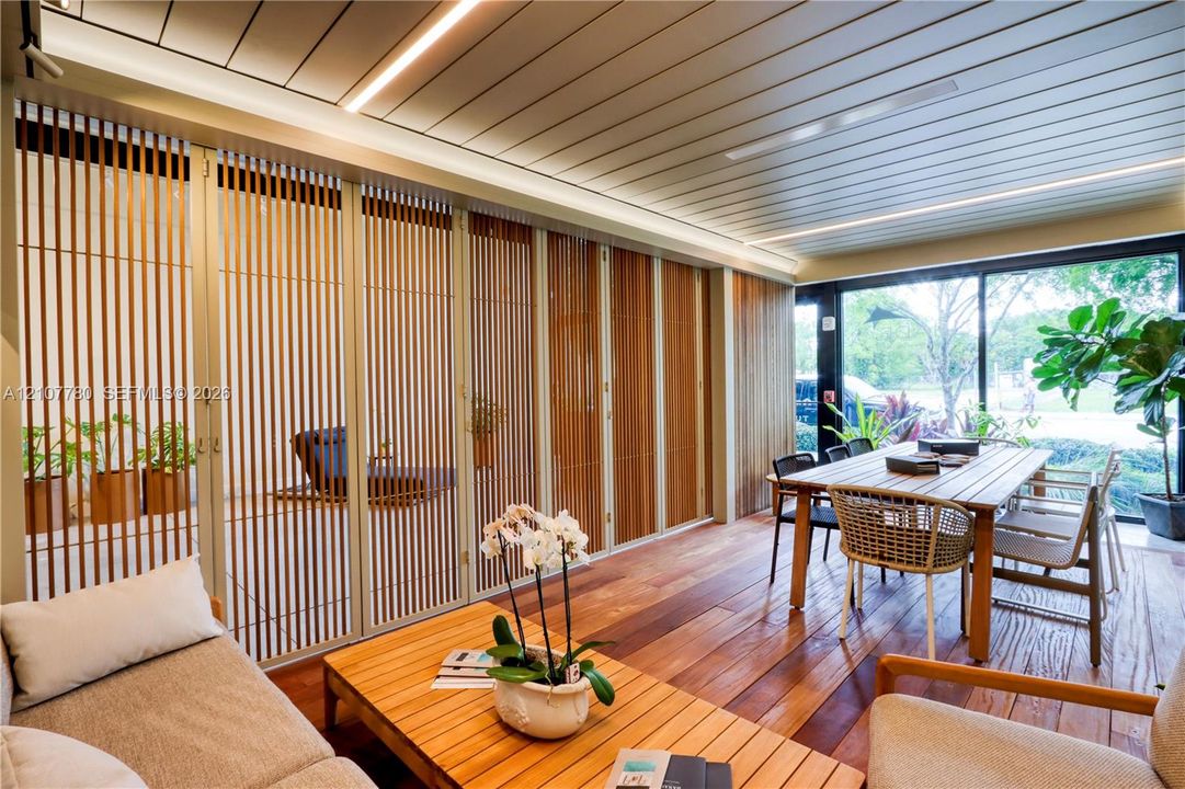 Covered outdoor living space featuring horizontal wood-finish ceiling planks, recessed linear lighting, wood-finish flooring, and vertical slatted privacy screening