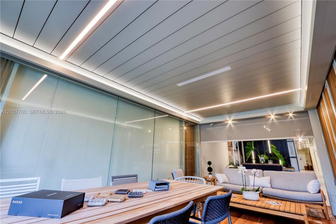 Linear panel ceiling featuring integrated LED strip lighting, extensive glass wall paneling, and wood-finish flooring
