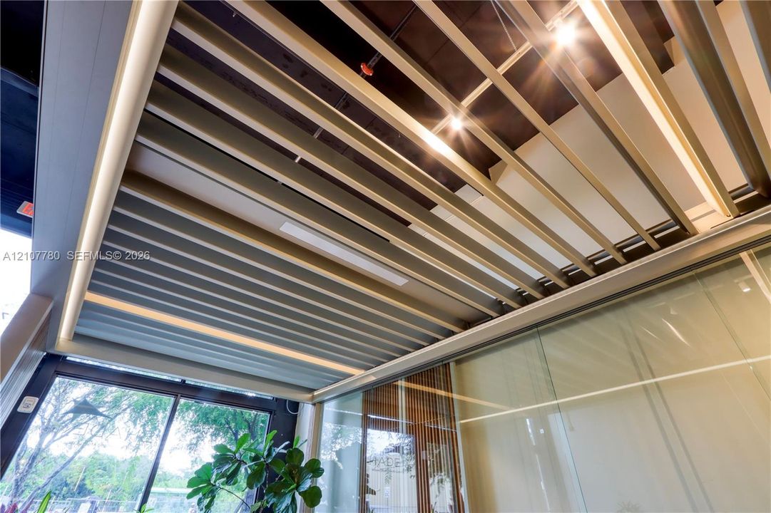 Retractable louvered roof system featuring integrated linear lighting, matte-finish metallic slats, and structural framing