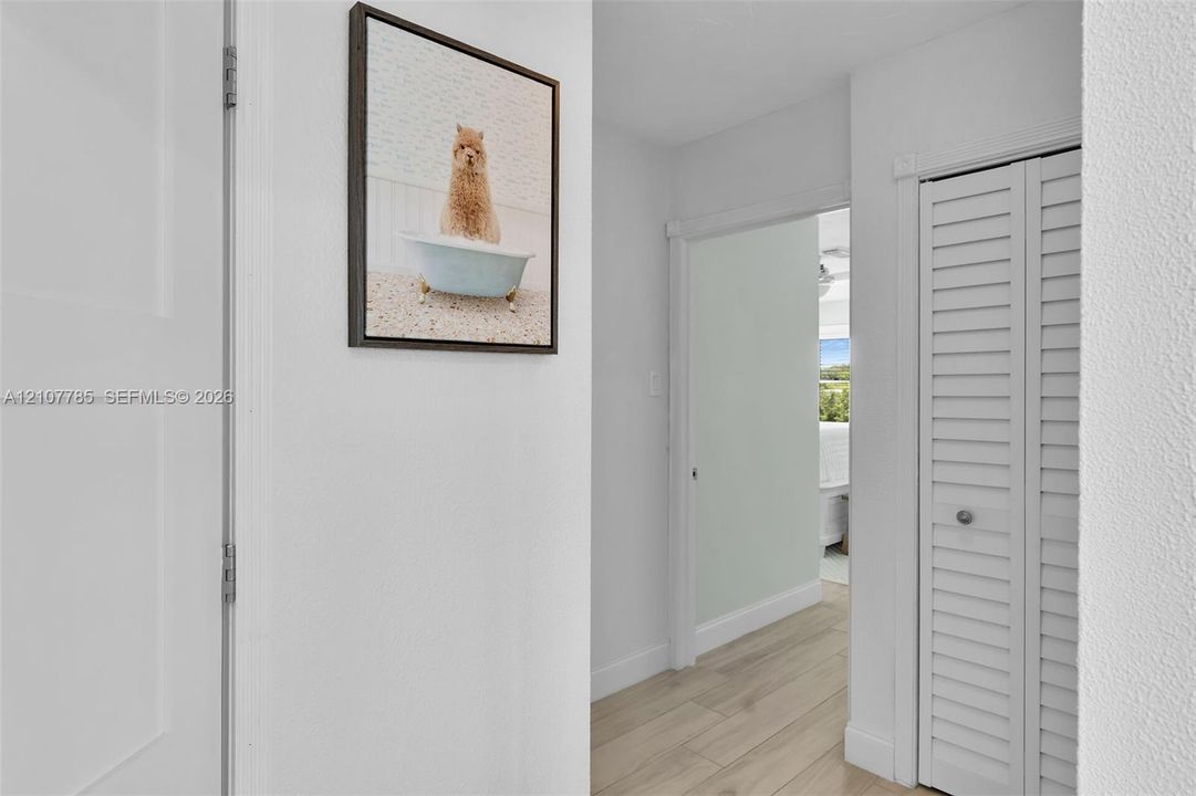 Hallway featuring wood-finish flooring and a closet with white louvered bi-fold doors