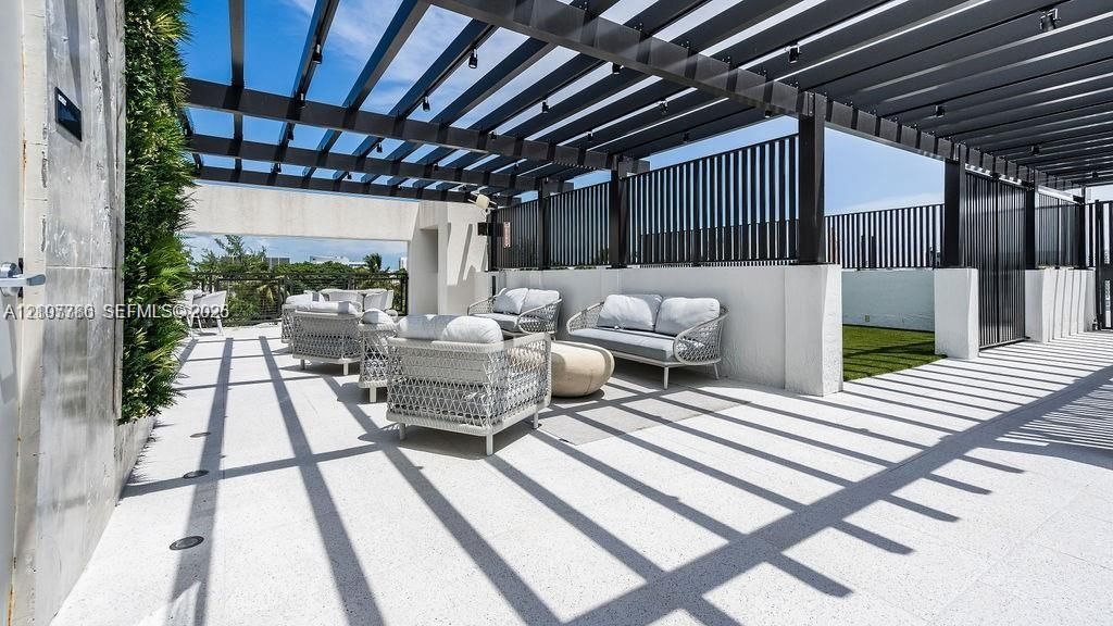 Rooftop terrace featuring a sprawling pergola, integrated recessed lighting, vertical slat privacy screening, a decorative green wall, and specialized aggregate flooring