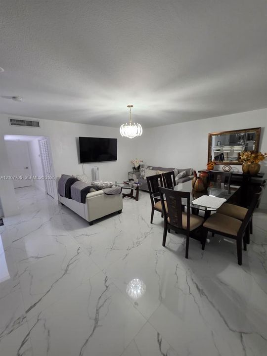 Large-format polished stone flooring with veined detailing, custom decorative pendant lighting, and neutral wall finishes