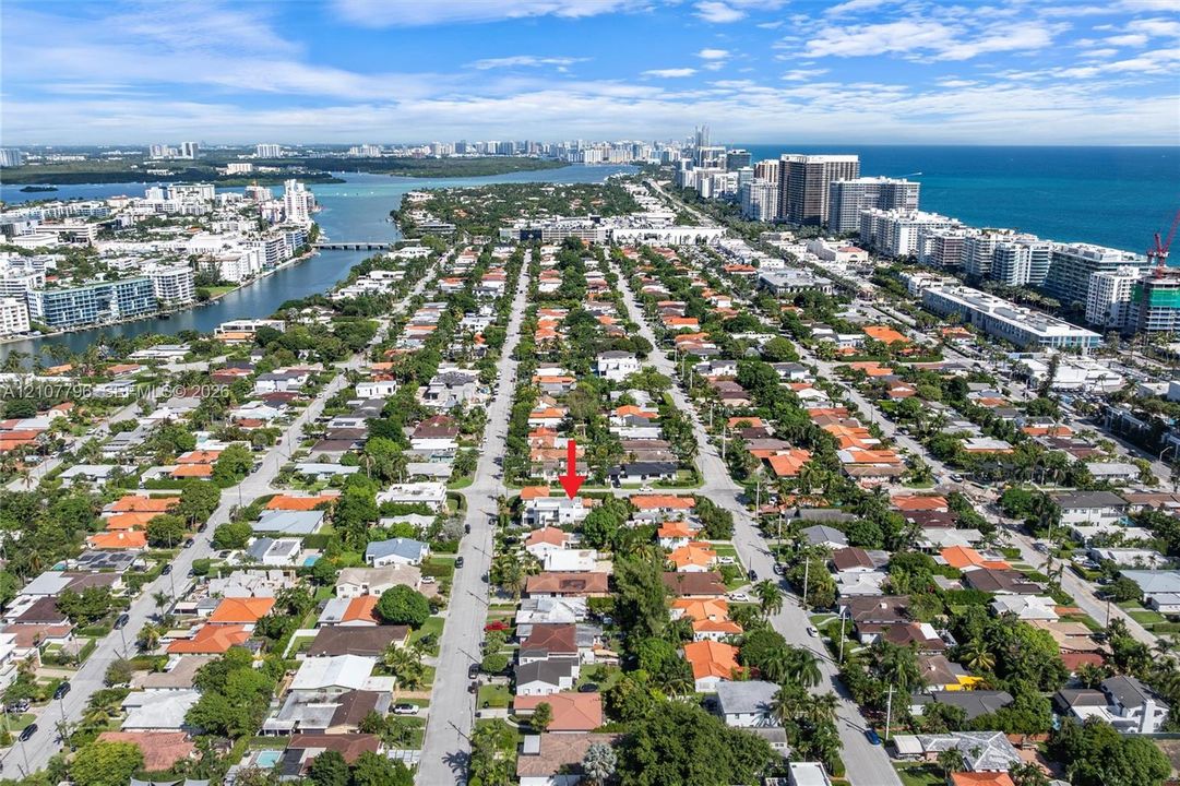 Aerial perspective of a residential lot situated within a coastal urban landscape, featuring proximity to waterfront waterways and high-density commercial districts