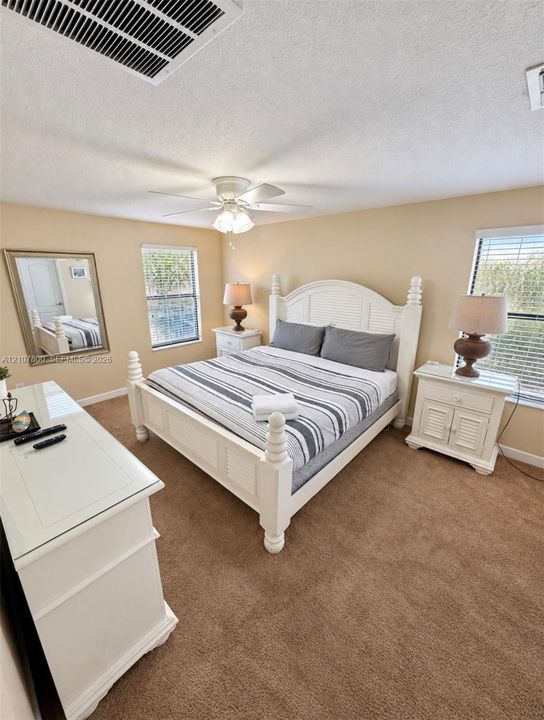 Carpeted room featuring multi-pane windows with horizontal blinds and an integrated ceiling fan with light fixture