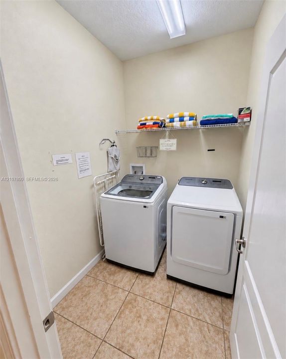 Laundry area featuring tile flooring, wire shelving, and overhead linear lighting