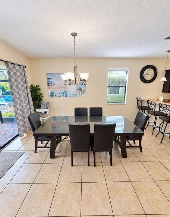 Dining area featuring ceramic tile flooring, a multi-arm metal chandelier, and a breakfast bar with stone-finish countertop