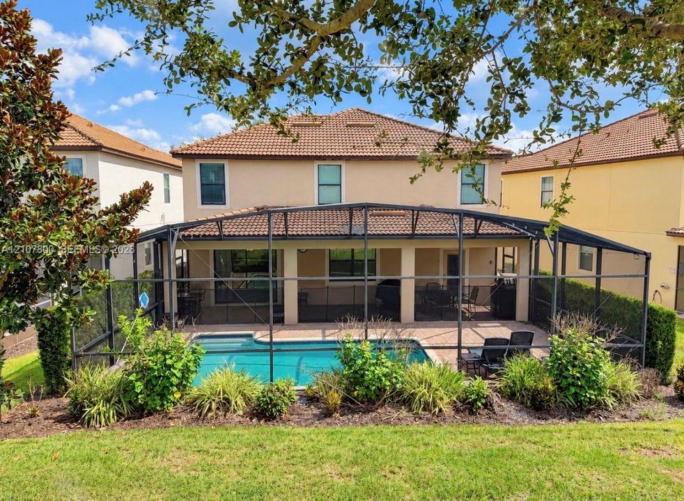 Screen-enclosed patio with a paved deck, private swimming pool, stucco exterior, and multi-pitched tile roof