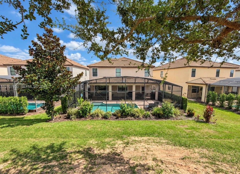 Stucco exterior residence featuring a screened-in lanai, private swimming pool, brick paver patio, and landscaped perimeter