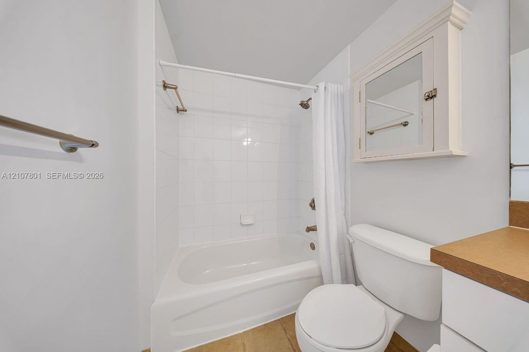 Bathroom featuring a white bathtub with tile surround, built-in medicine cabinet with integrated mirror, and metallic hardware finish