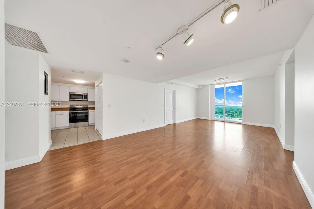 Open interior space featuring wood-finish flooring, track lighting, and floor-to-ceiling glass sliding doors