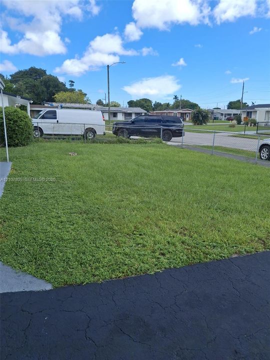 Expansive lawn area featuring chain-link perimeter fencing and an asphalt driveway