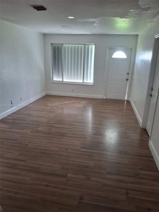 Interior room featuring wood-finish flooring, white walls, recessed ceiling lighting, a multi-pane window, and an exterior door with a semi-circular glass insert