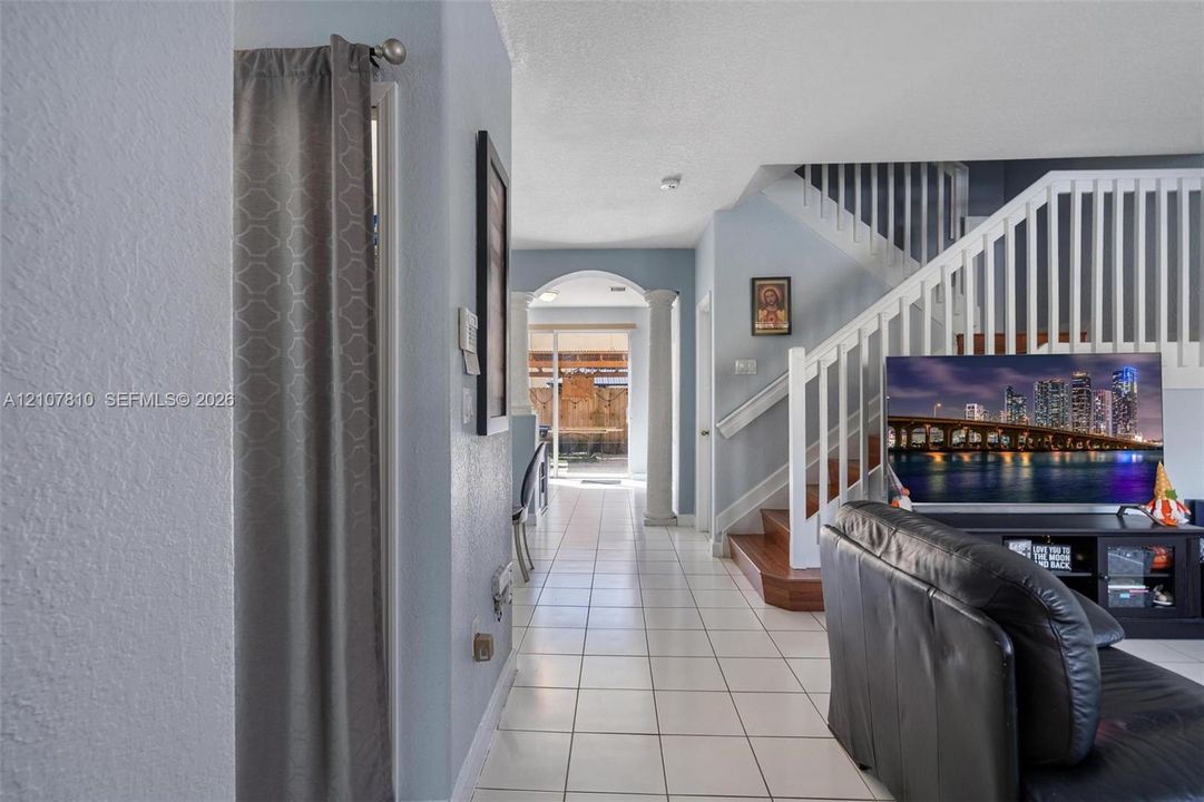 Ceramic tile flooring, white wooden staircase railing, and architectural columns