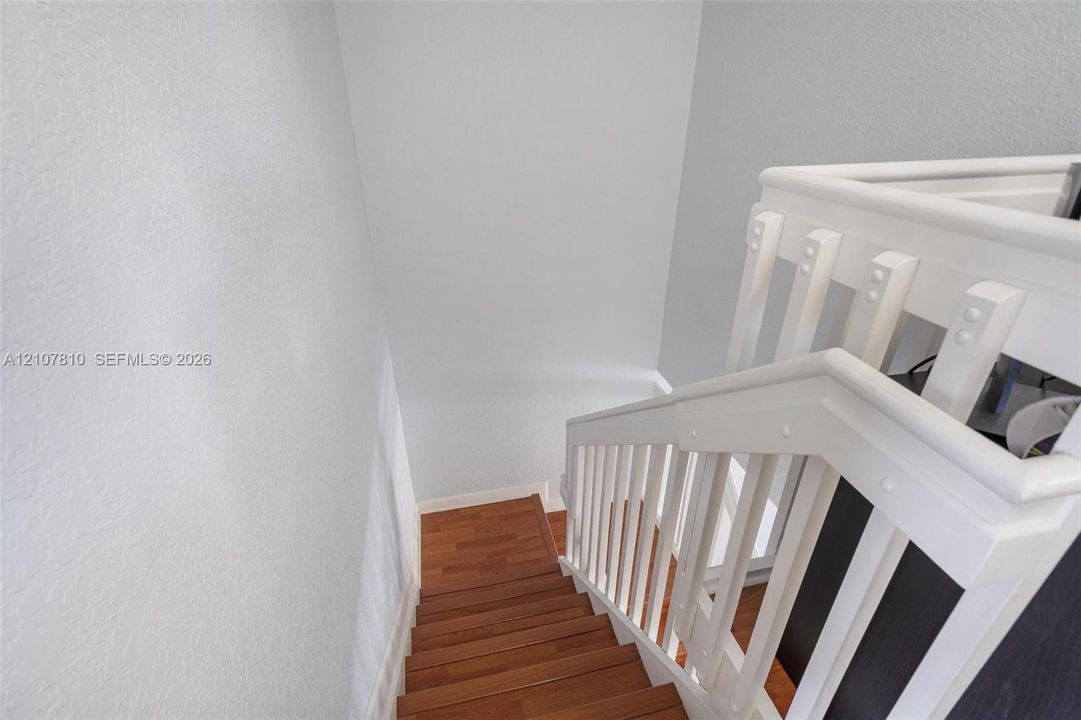 Staircase featuring wood-finish treads and white painted balustrade with a matching handrail