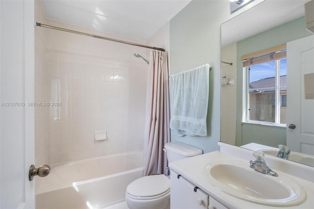 Bathroom featuring a white vanity with an integrated sink, polished chrome faucet, full-width mirror, and a tub-shower combination with tiled surround