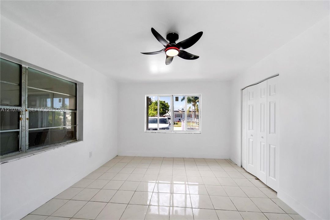 Interior space featuring polished ceramic tile flooring, dual-pane aluminum windows, and a modern ceiling fan with integrated lighting, complemented by a built-in bifold closet
