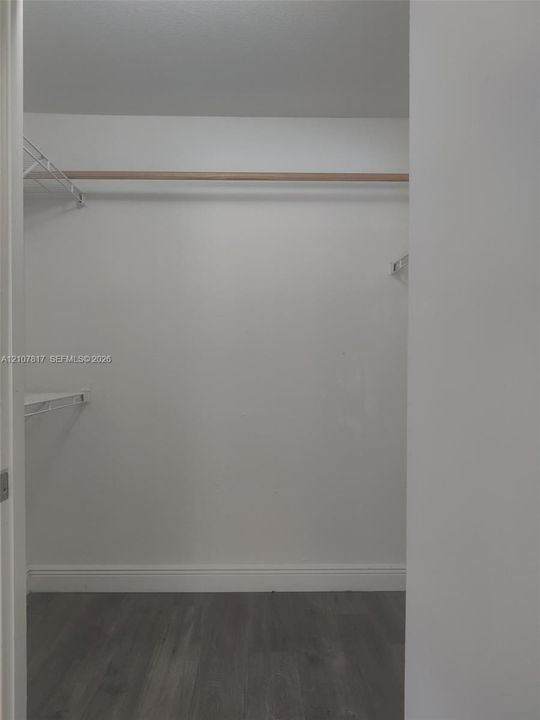 Storage space featuring wood-finish flooring, a full-width hanging rod, and wire shelving