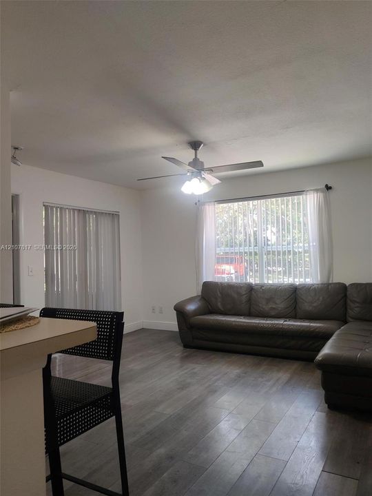 Wood-finish flooring, ceiling fan with integrated lighting, and vertical window blinds