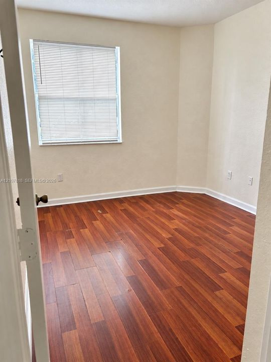 Neutral interior featuring wood-finish flooring and a window with horizontal blinds