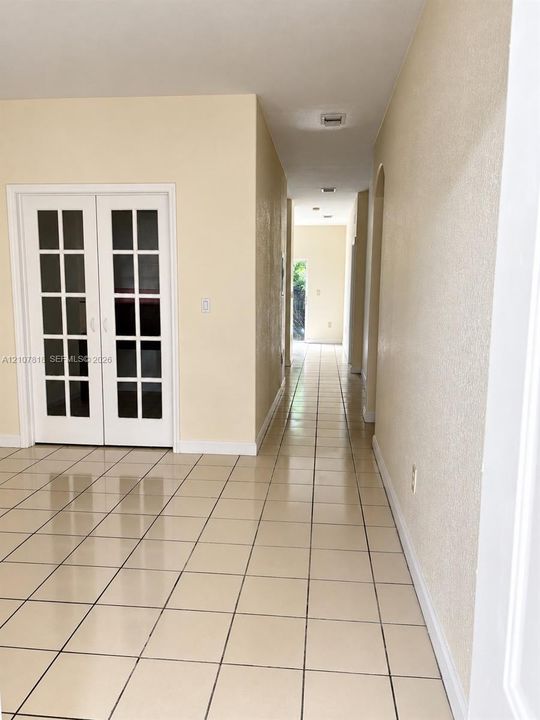 Neutral-toned tiled flooring, white-framed French doors, and smooth-finish walls