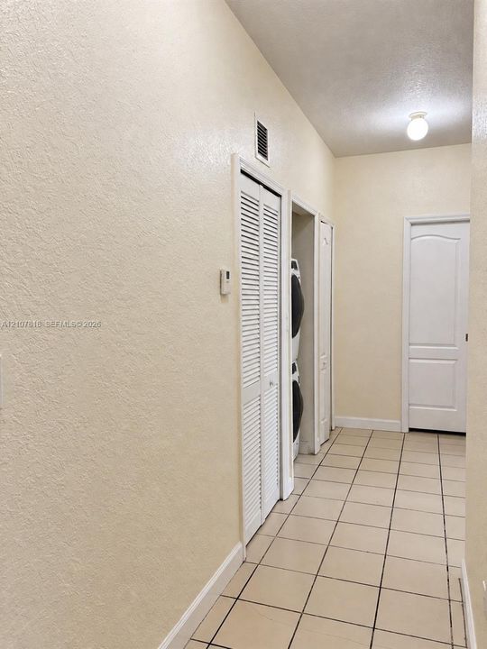 Interior space featuring neutral wall tones, ceramic tile flooring, a dedicated laundry closet with louvered bi-fold doors, and a paneled interior door