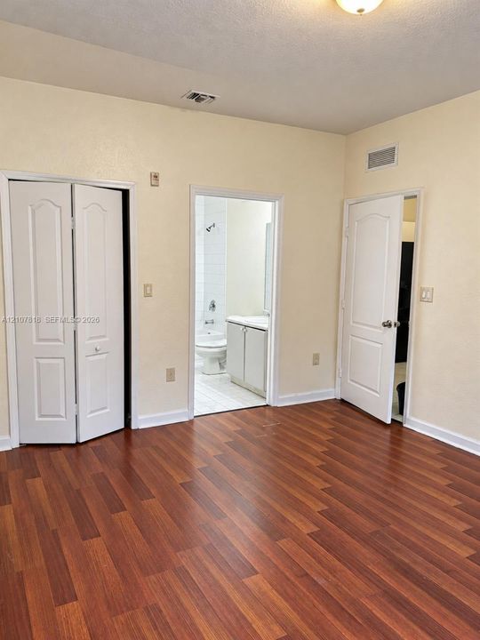 Room featuring wood-finish flooring, white paneled interior doors, and built-in closet storage