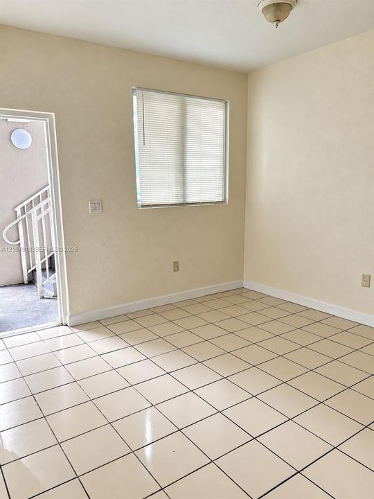 Neutral-toned room featuring tile flooring, a window equipped with horizontal blinds, and a semi-flush mount ceiling fixture