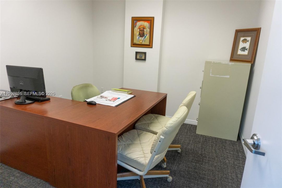 Interior room featuring neutral wall paint, gray textured carpeting, and a polished metal door handle