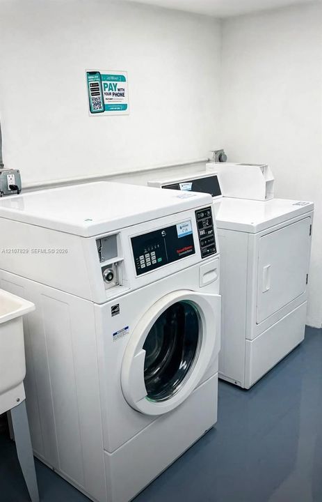 Laundry area featuring a front-loading washing machine, a top-loading dryer, and a utility sink with smooth surface flooring