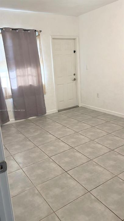 Neutral-toned ceramic tile flooring, solid-panel entry door, and multi-pane window