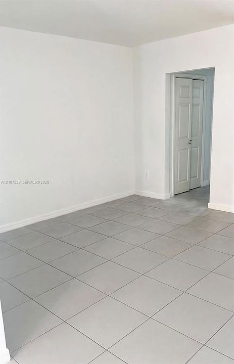 Neutral-toned tile flooring and white walls featuring a classic six-panel bi-fold door