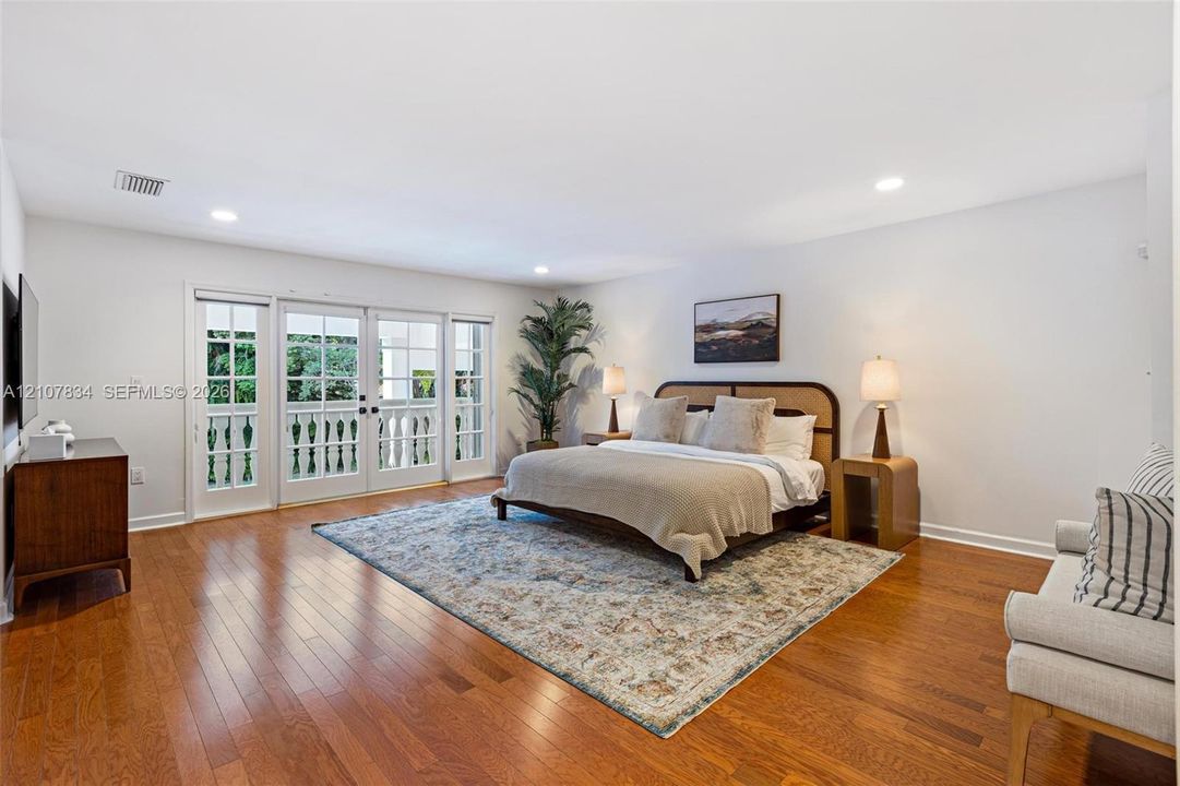 Spacious room featuring wood-finish flooring, recessed lighting, and multi-panel glass doors with a decorative railing
