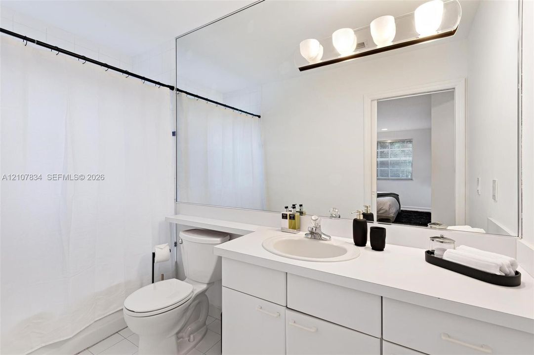 Full-width vanity mirror, vanity with integrated sink and countertop, and four-light horizontal fixture