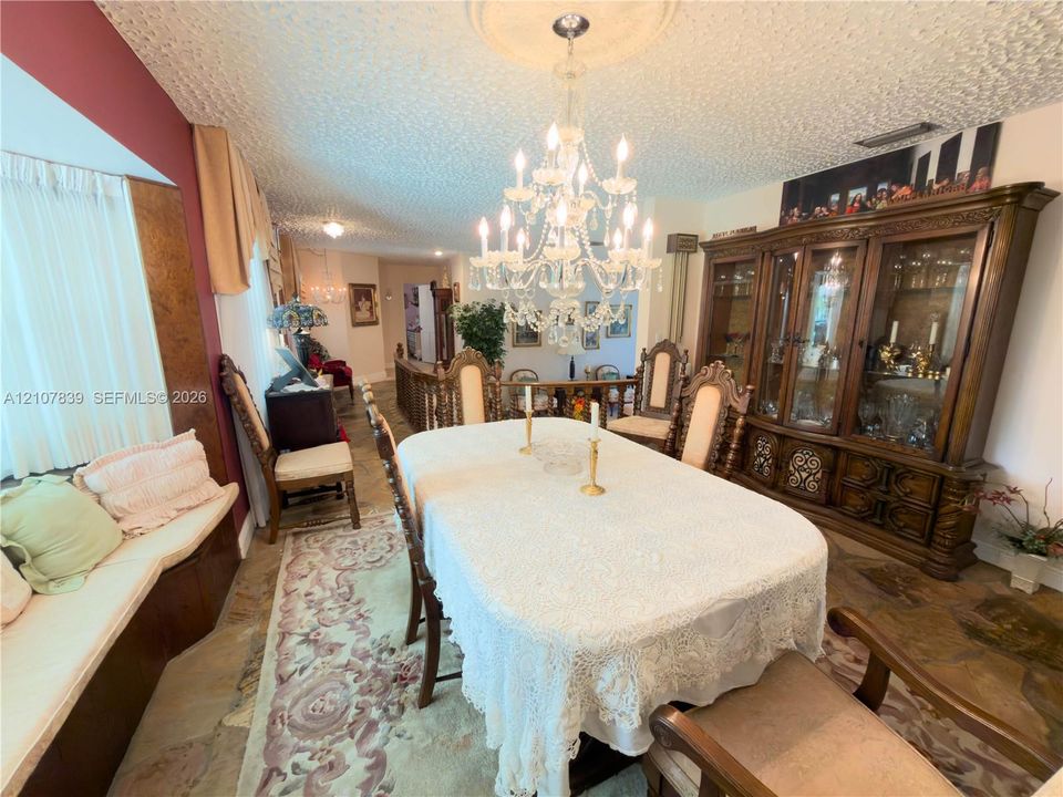 Dining area featuring a built-in window seat, ornate crystal chandelier with ceiling medallion, and custom built-in wooden cabinetry